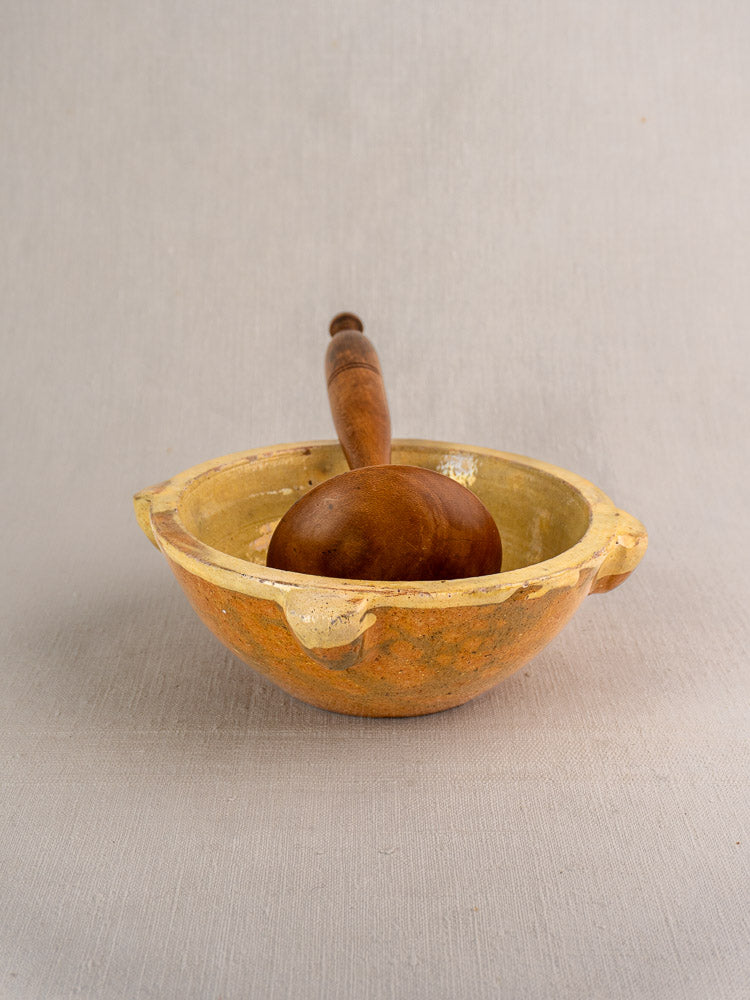 Late 19th century French yellow glazed mortar with three spouts and wooden pestle on neutral surface.