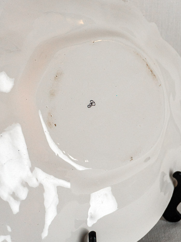 Underside of 19th-century Moustiers French faience platter with central black infinity symbol and minor stains.