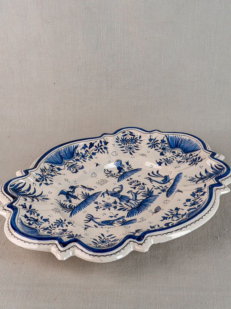 Antique French Moustiers faience platter with scalloped edge, blue floral and bird motifs on white.