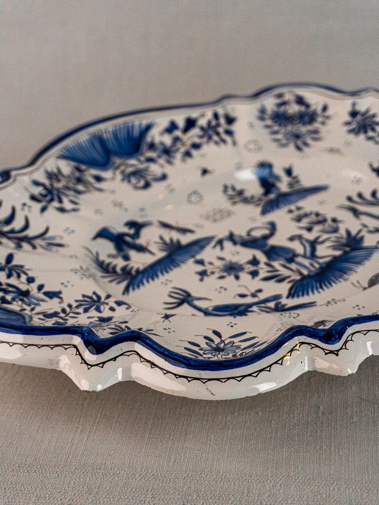 Antique French Moustiers faience platter with blue floral and bird décor à grotesques on white scalloped ceramic.