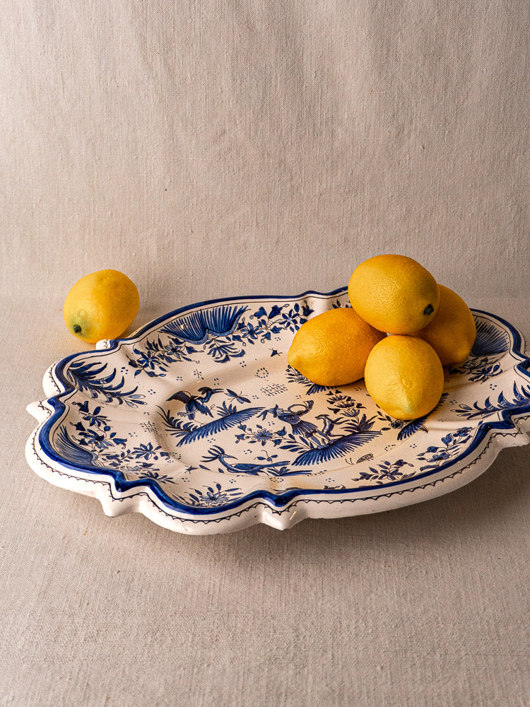 19th-century French faience Moustiers blue and white platter with six lemons on neutral fabric.