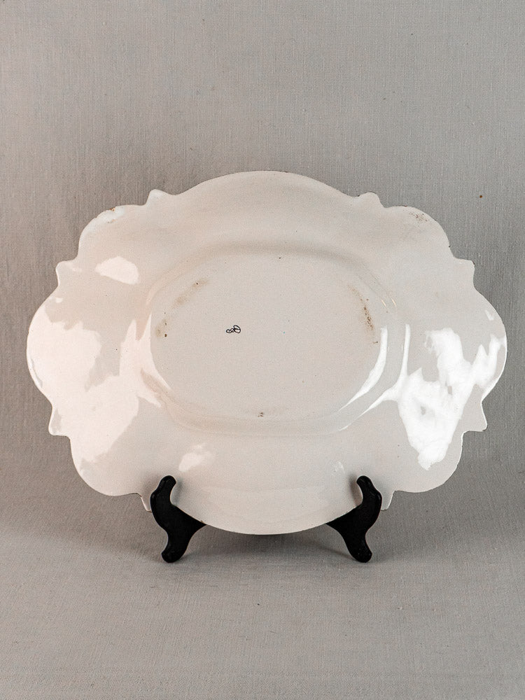 19th-century French faience Moustiers oval platter with blue-and-white grotesque décor, scalloped edges, light staining.