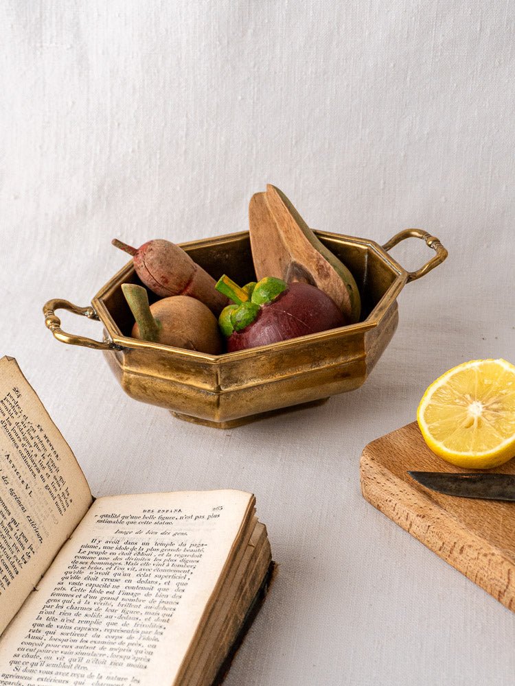 Small antique French octagonal brass bowl with two ornate handles on a light background.