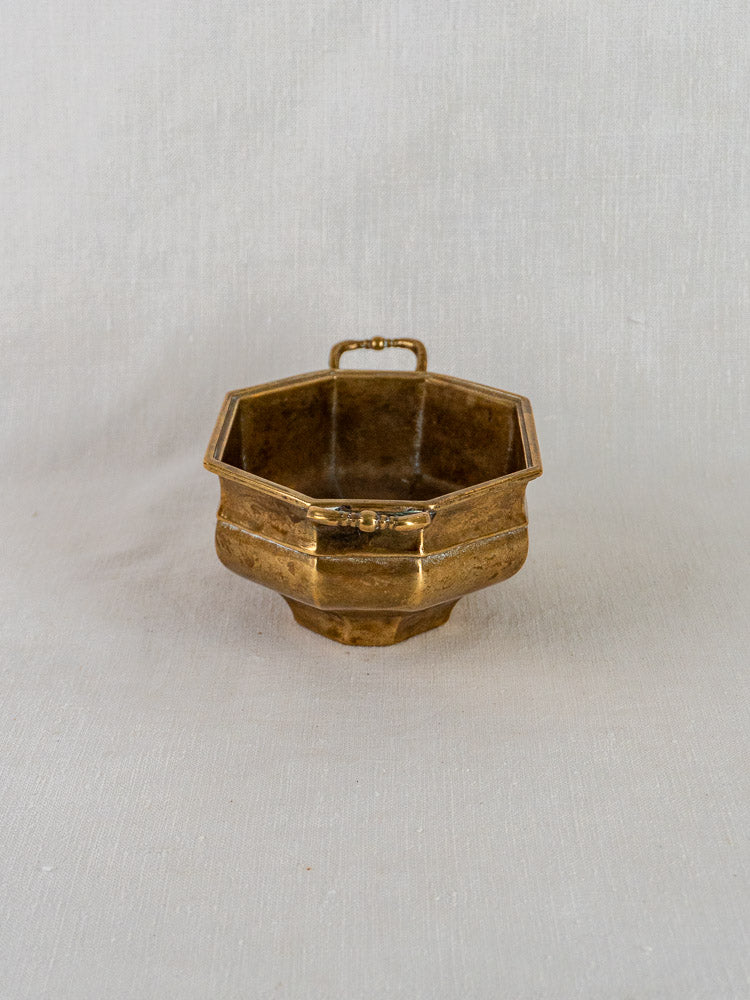 Antique French brass octagonal coupe with two handles on a light fabric background.