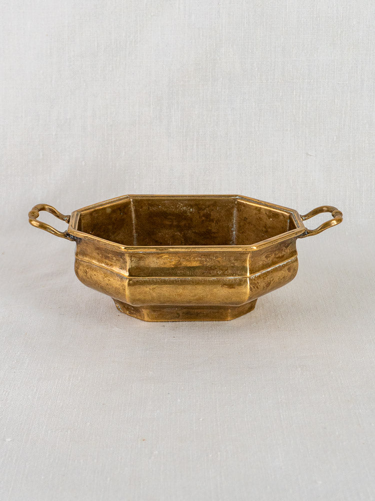 Antique French brass octagonal coupe with two handles, displayed on a light textured surface.