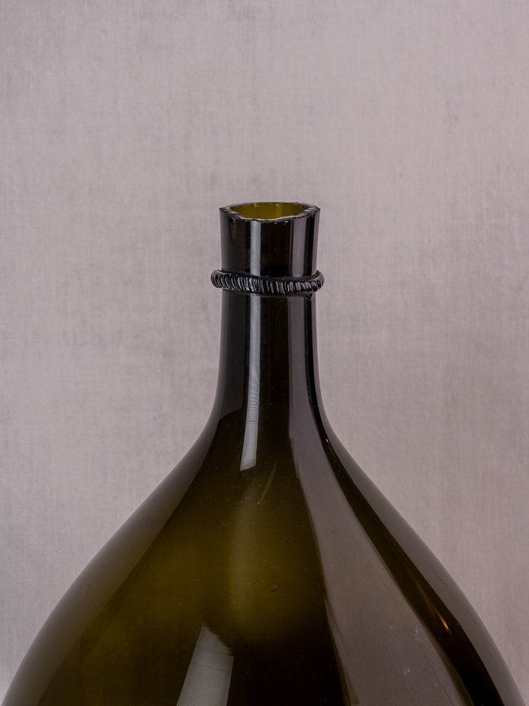 Antique French olive green demijohn with applied neck ring in glossy hand-blown glass, set against a light background.