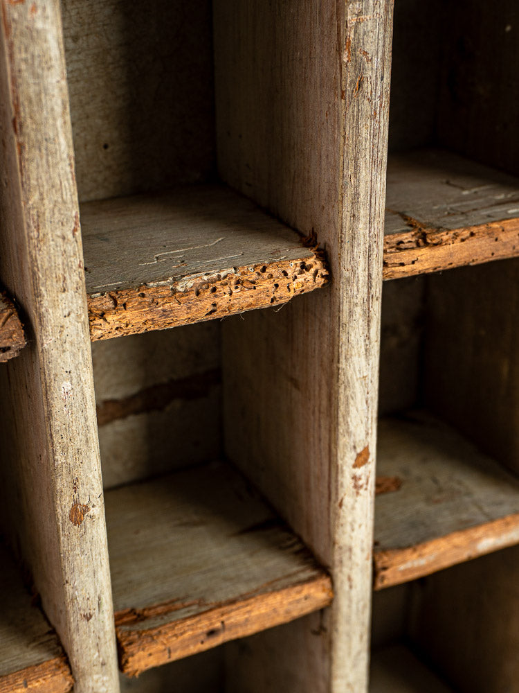 Antique French painted pine casier with nine compartments, weathered wood, rough edges, and peeling paint.