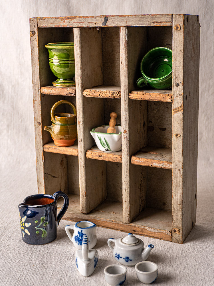 Antique French painted pine casier with nine compartments showcasing miniature ceramic mugs, teapots, and bowls.