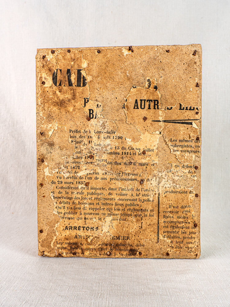 Aged French paper with brown stains, torn edges, and holes on a light neutral background.