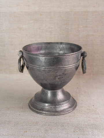 Antique French mid-19th century pewter footed bowl with side handles on textured beige fabric background.