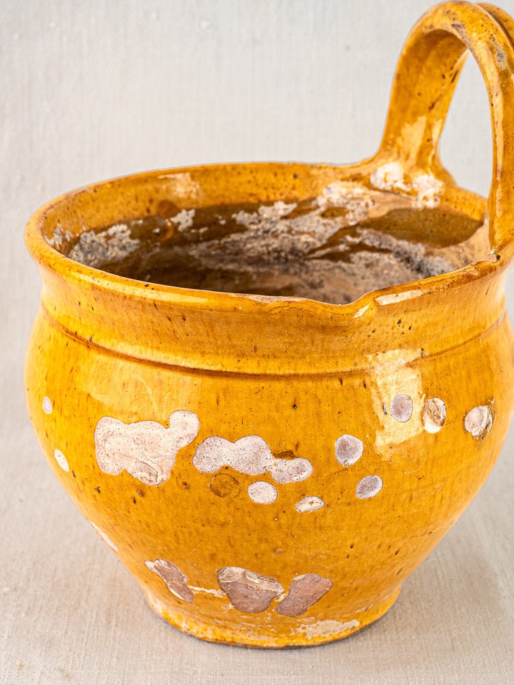 19th-century French yellow glazed terracotta hanging planter with large handle and worn clay accents.