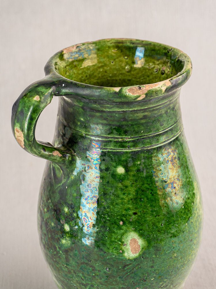 Antique French green glazed terracotta pitcher with handle, aged glaze reveals ceramic underneath.