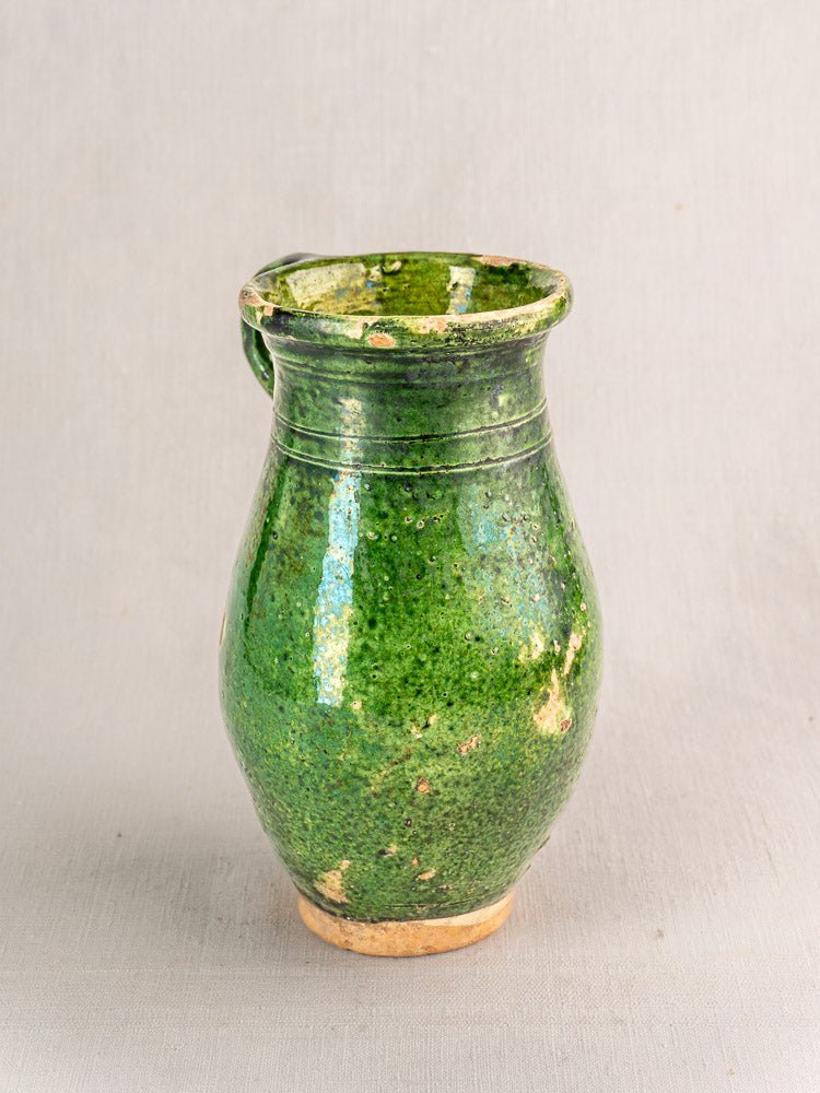 Antique 19th-century French green glazed terracotta pitcher with wide body and single handle.