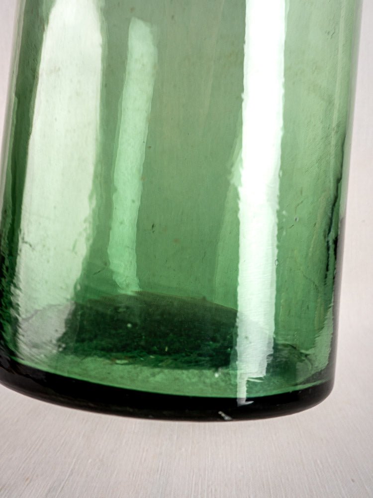 Antique French hand-blown green bubble glass preserves bottle base, textured surface, reflective highlights.