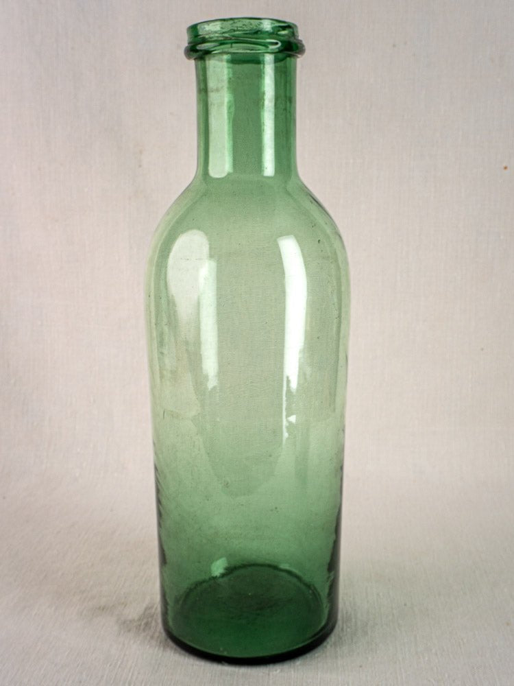 Antique French green bubble glass preserves bottle, hand-blown circa 1900, on a light surface.