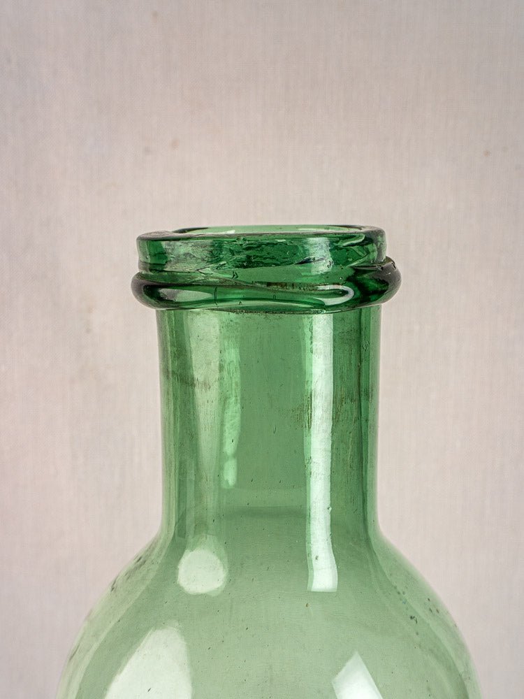 Antique French hand-blown green bubble glass preserves bottle neck and collar, light background.