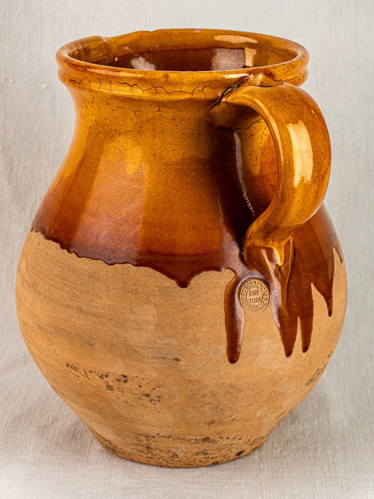 Vintage French Provençal pitcher with amber-brown glazed ceramic, textured finish, and maker’s mark near handle.