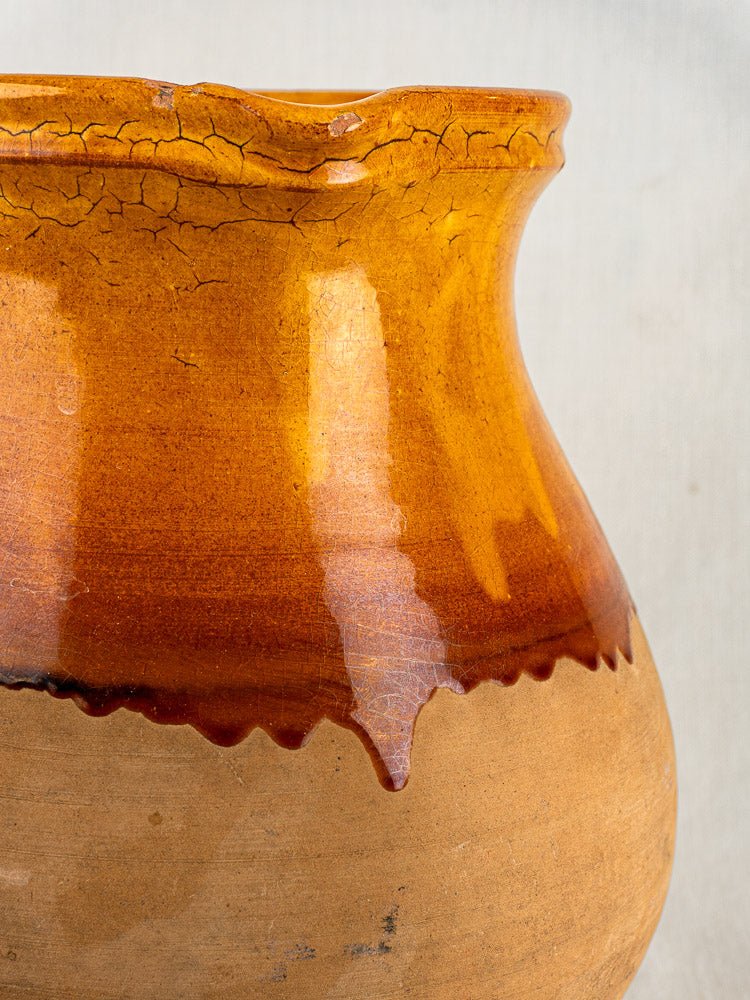 Vintage French Provençal terracotta pitcher with wavy rim, glossy amber glaze, matte unglazed base.