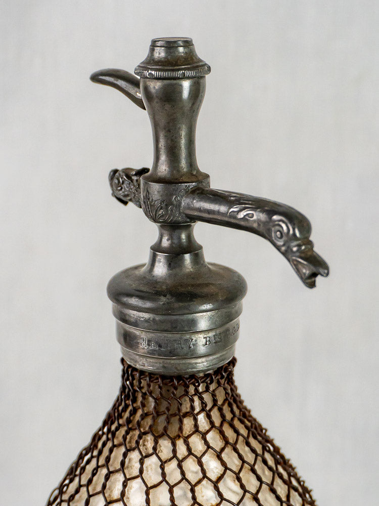Antique French Henry Paris Seltzer Siphon with wire mesh glass and ornate bird-shaped spout detailing.