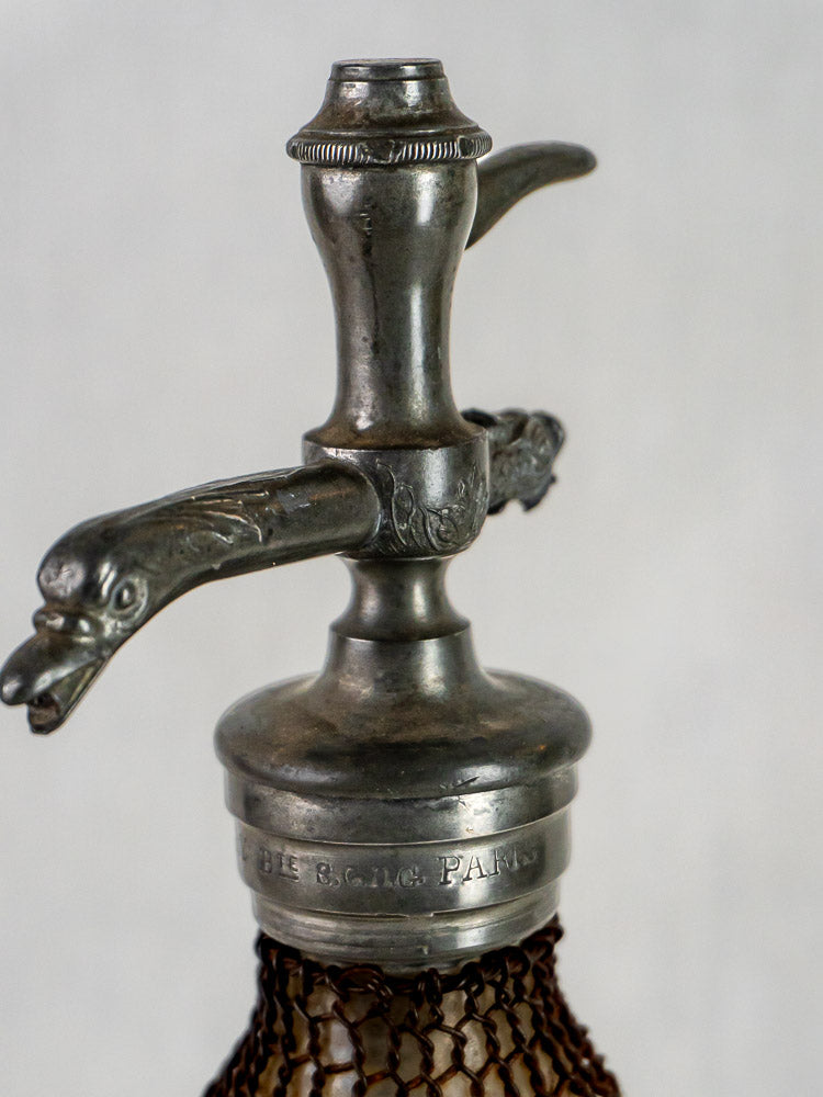 Antique French Henry Paris Seltzer Siphon with engraved metal top and intricate wire mesh wrapping.