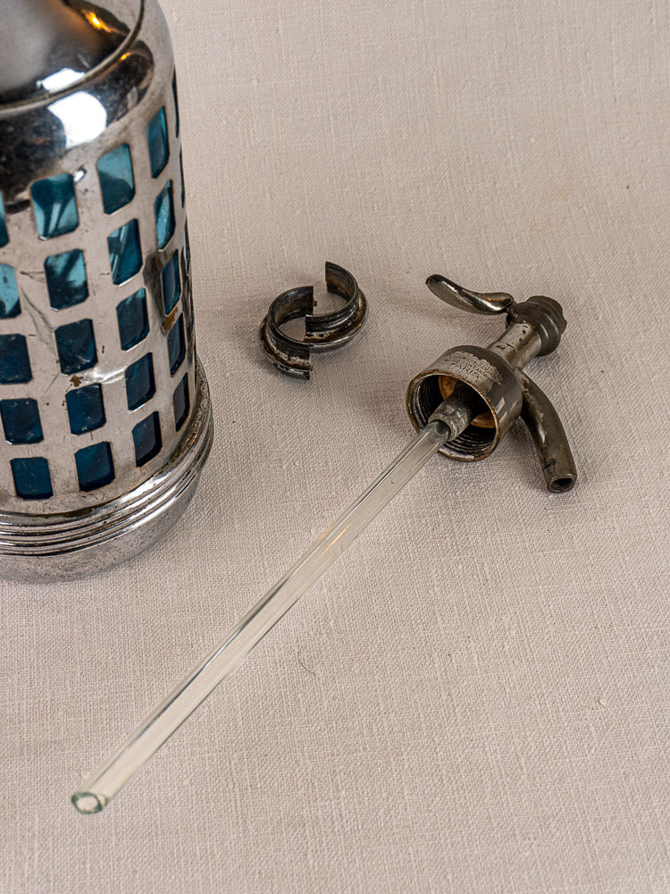 Antique French soda siphon with metal and blue glass, Paris bistro style, shown on beige fabric with detached part.