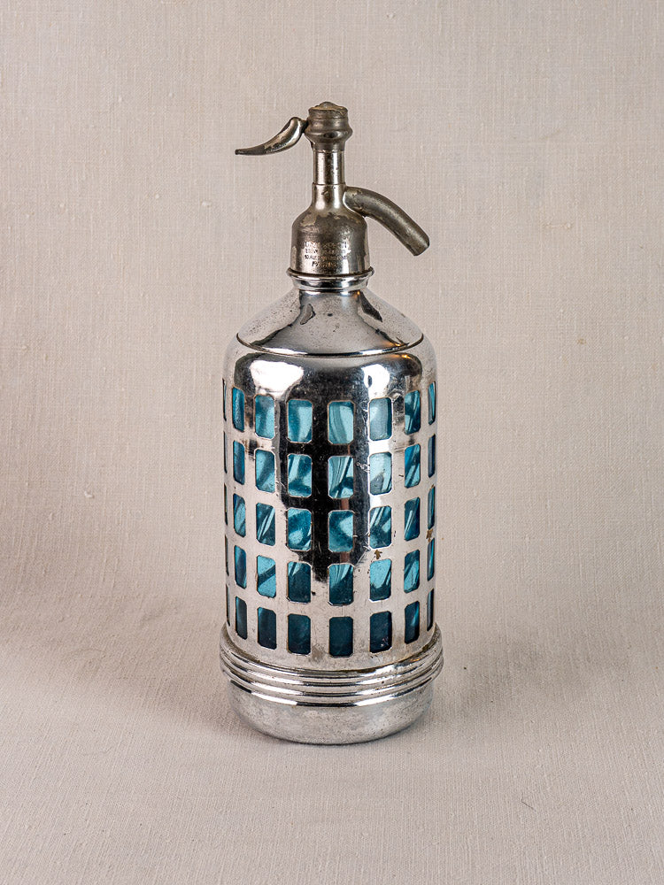 Antique French soda siphon with metal top, blue checkered pattern, and silver cage on a neutral surface.