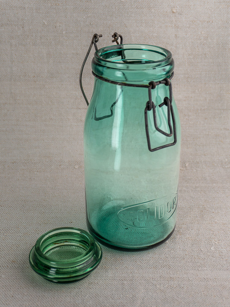 Set of three antique French Solidor & Durfor green glass preserve jars with embossed logos and metal clasps, on a light surface.
