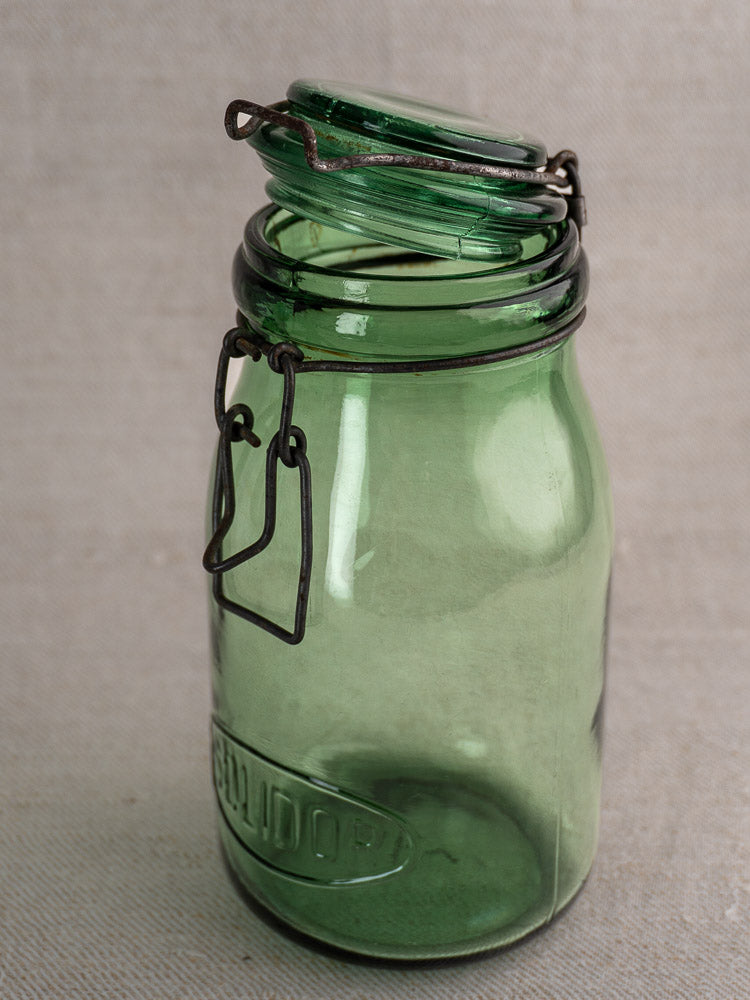 Set of three antique French Solidor & Durfor preserve jars with metal clasps on neutral fabric surface.