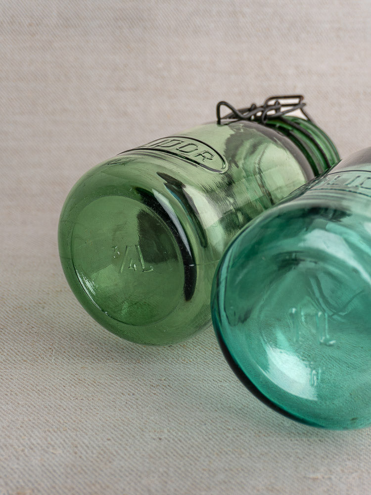 Set of three antique French Solidor and Durfor preserve jars on textured linen, front jar green with wire bail lid and embossing.
