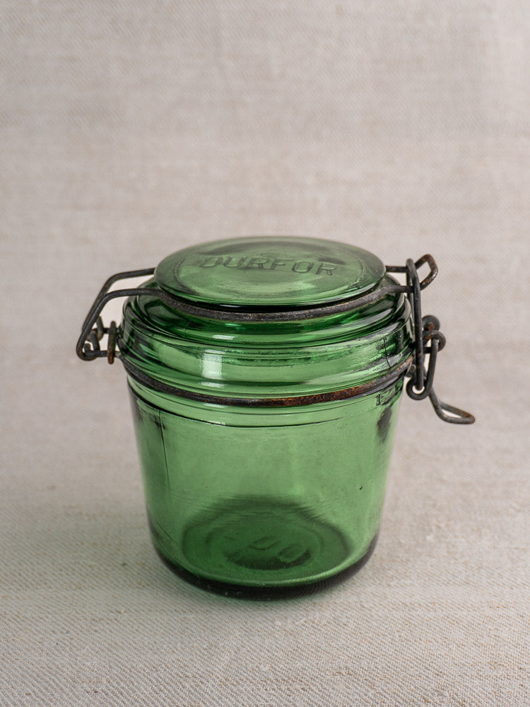 Set of 3 antique French Solidor & Durfor green glass preserve jars with metal clasps on neutral fabric background.