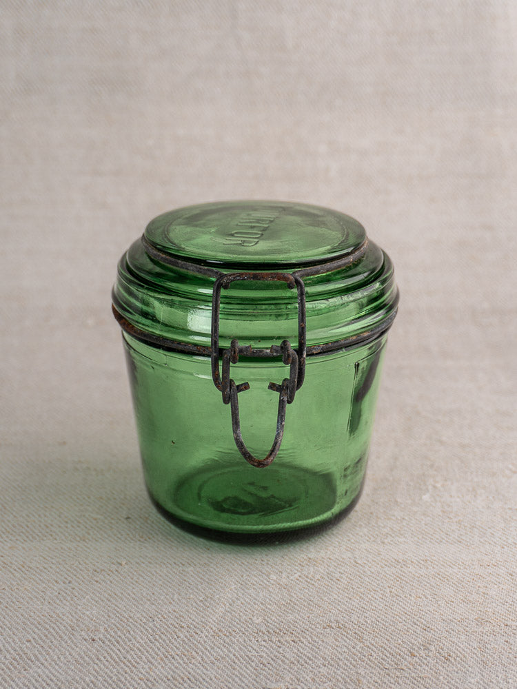 Set of three antique French Solidor & Durfor preserve jars in vintage green glass with metal clasps on beige textured surface.