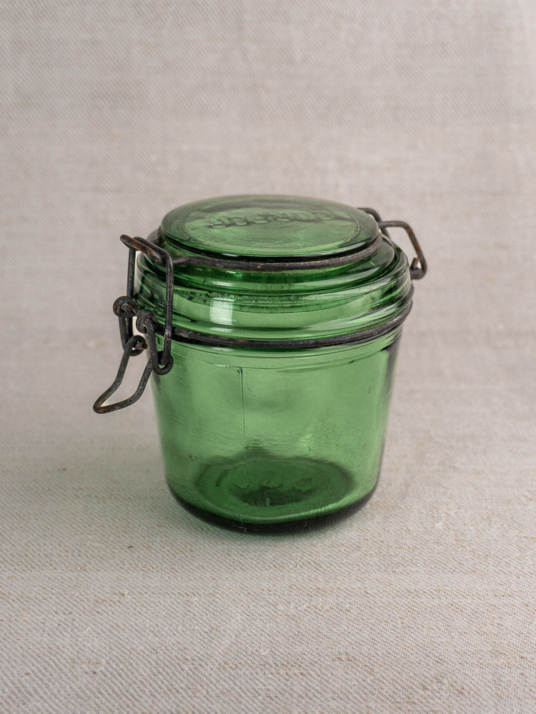 Set of three antique French Solidor & Durfor green glass preserve jars with metal clasps, on neutral textured fabric.