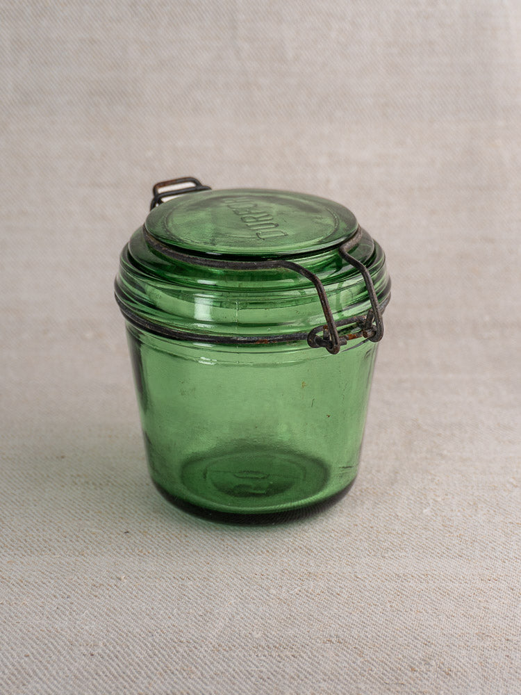 Set of three antique French Solidor & Durfor preserve jars with lids and metal clasps on light textured fabric.