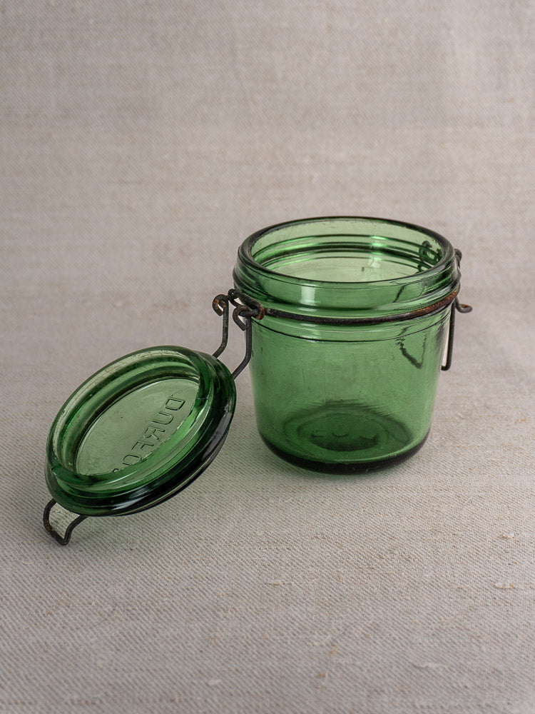 Antique French preserve jar from the Solidor & Durfor set, open with metal clasp lid, on neutral fabric background.