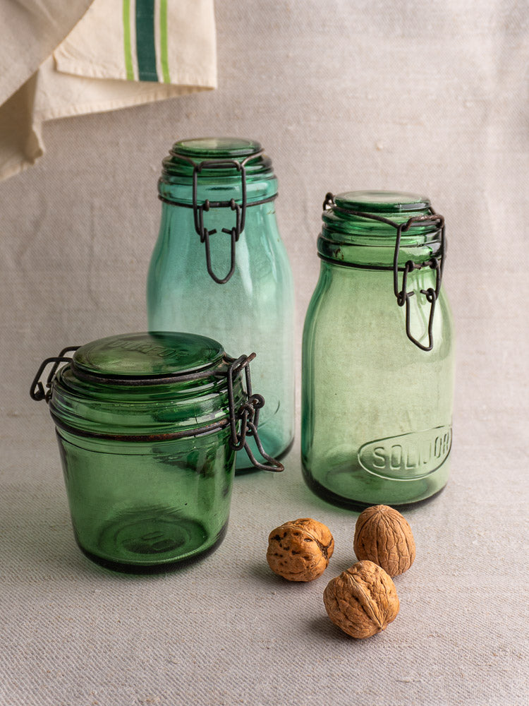 Set of three antique French preserve jars by Solidor & Durfor with metal clasps, on fabric with walnuts.