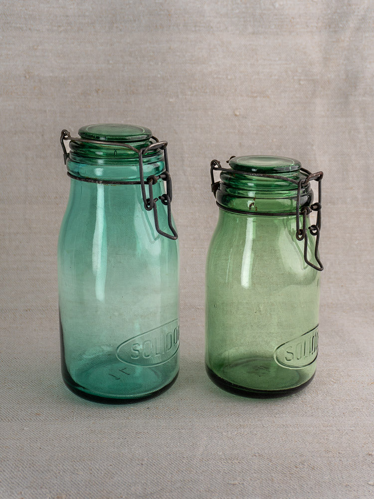 Set of three antique French Solidor and Durfor preserve jars with embossed script, metal lids, and vintage green glass.