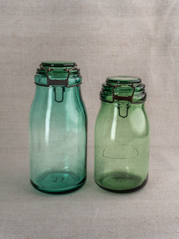 Set of three antique French Solidor & Durfor preserve jars with metal clasps, embossed ovals, on neutral fabric.