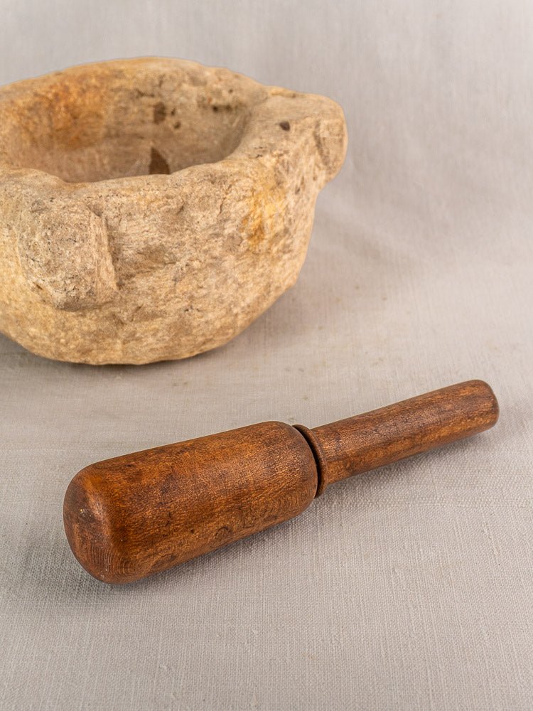 Antique French stone mortar and pestle, hand-carved Provençal mortier, set on a light fabric surface.