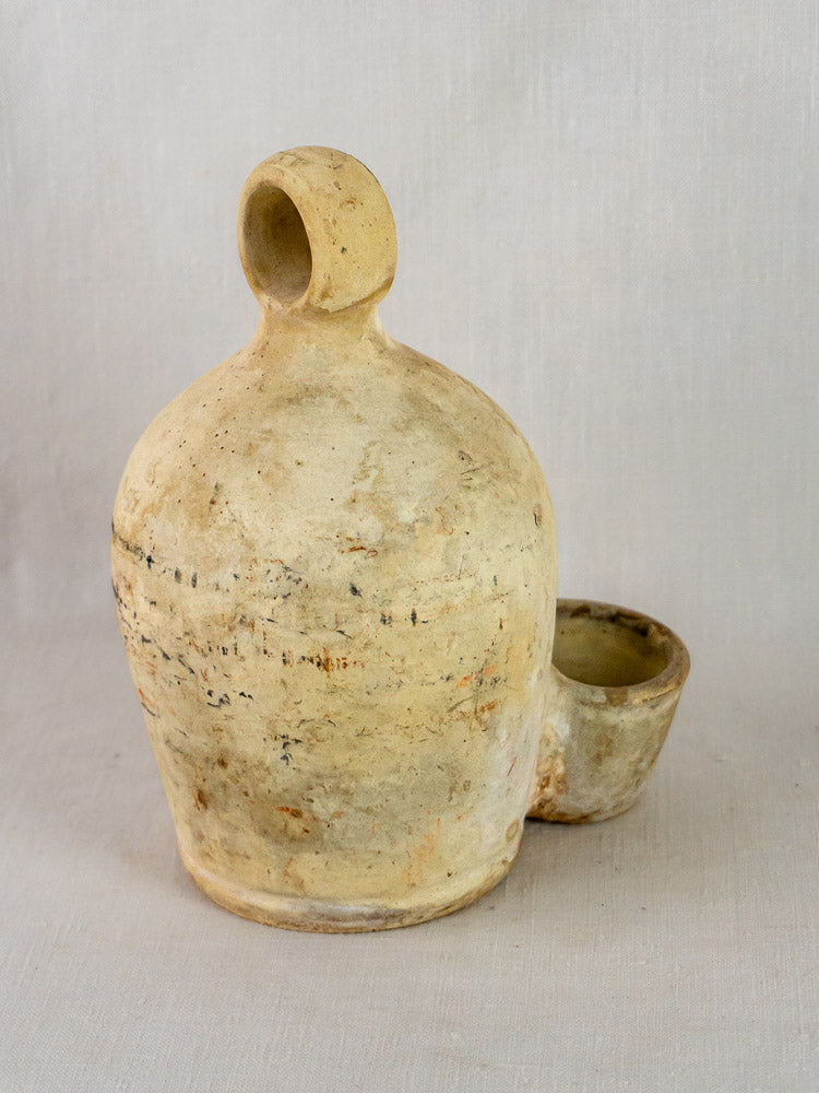 Antique French stoneware bird waterer in beige ceramic with round body and side cup.