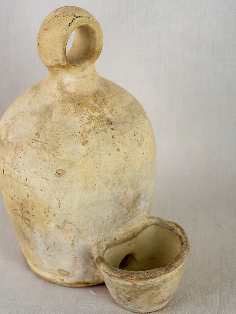 Antique French stoneware bird waterer and matching cup, rustic beige ceramic on neutral background.