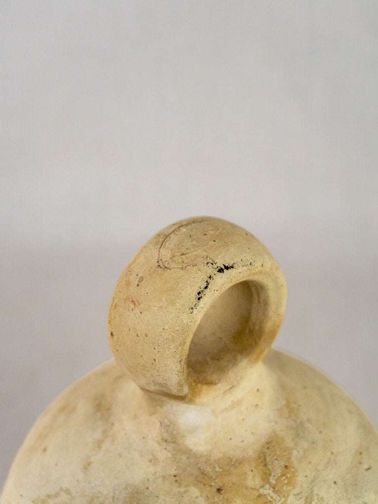 Handle detail of antique French stoneware bird waterer in beige ceramic with weathered texture.