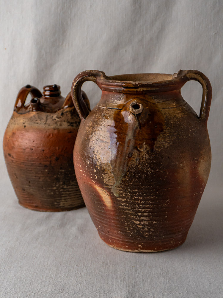 Pair of early 19th-century French stoneware oil jugs with ochre glaze and earthy patina.