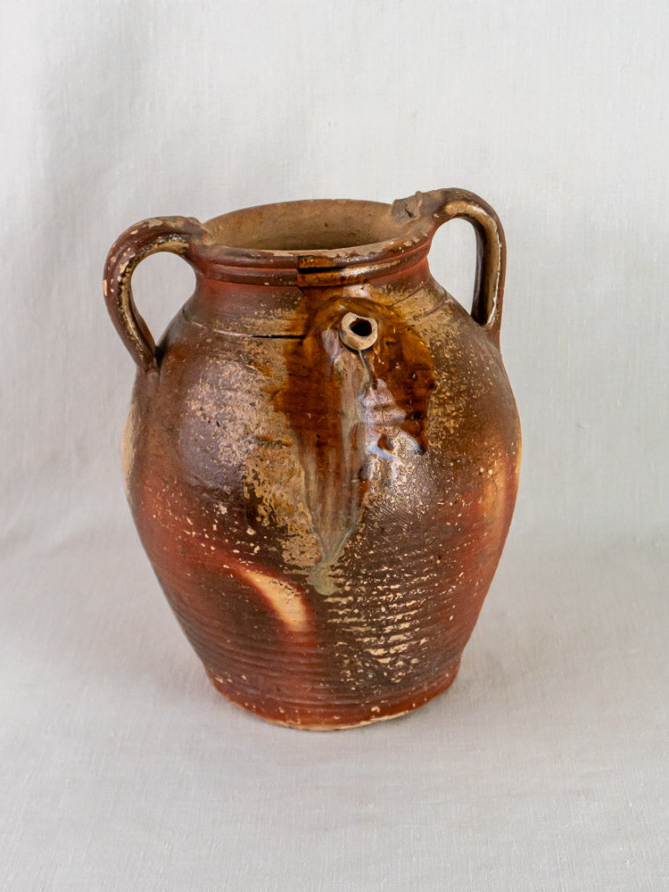 Early 19th-century French stoneware oil jug with ochre glaze, two handles, and textured finish.