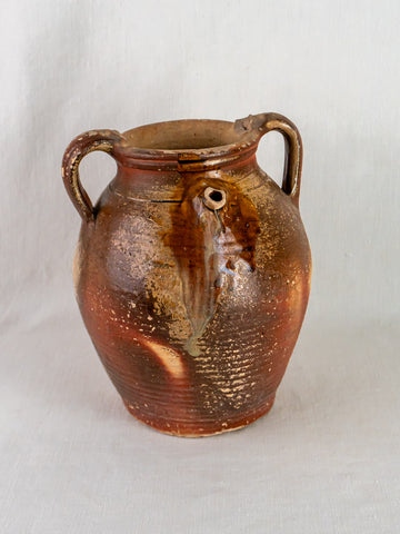 Early 19th-century French stoneware oil jug with ochre glaze, two handles, and textured finish.