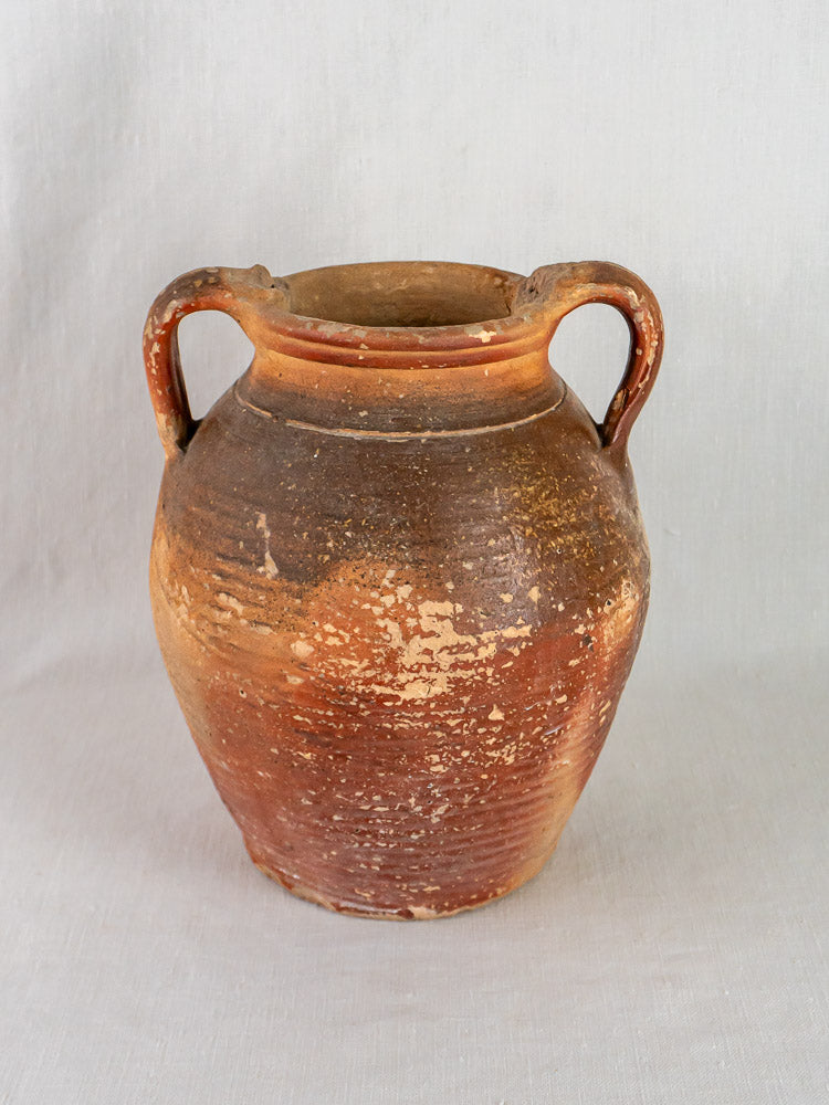 Antique French stoneware oil jug with ochre glaze, two handles, reddish-brown grès; light gray background.