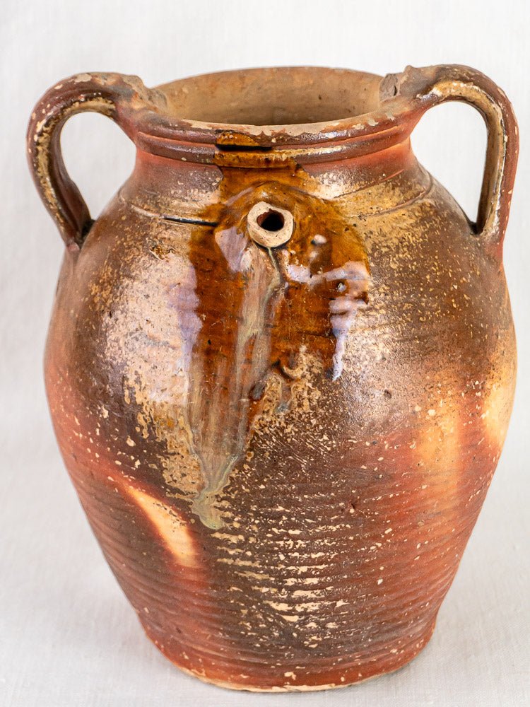 Early 19th-century French stoneware oil jug with ochre glaze, two handles, and rustic texture.