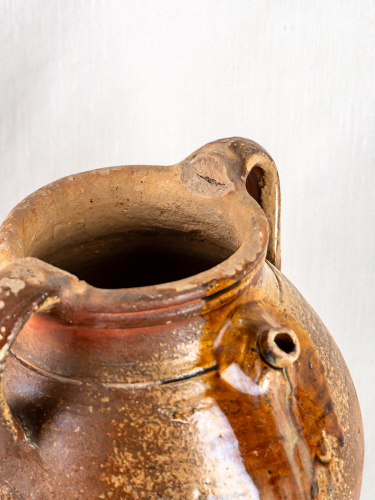Antique French stoneware oil jug, early 19th century, ochre glaze, two handles, worn texture.