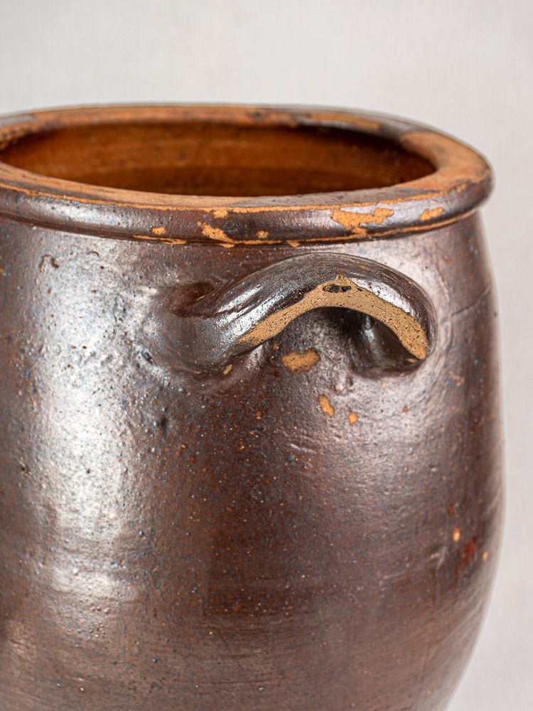 Antique French salt-glazed stoneware pot à graisse with curved handle, textured surface, and rim chips.