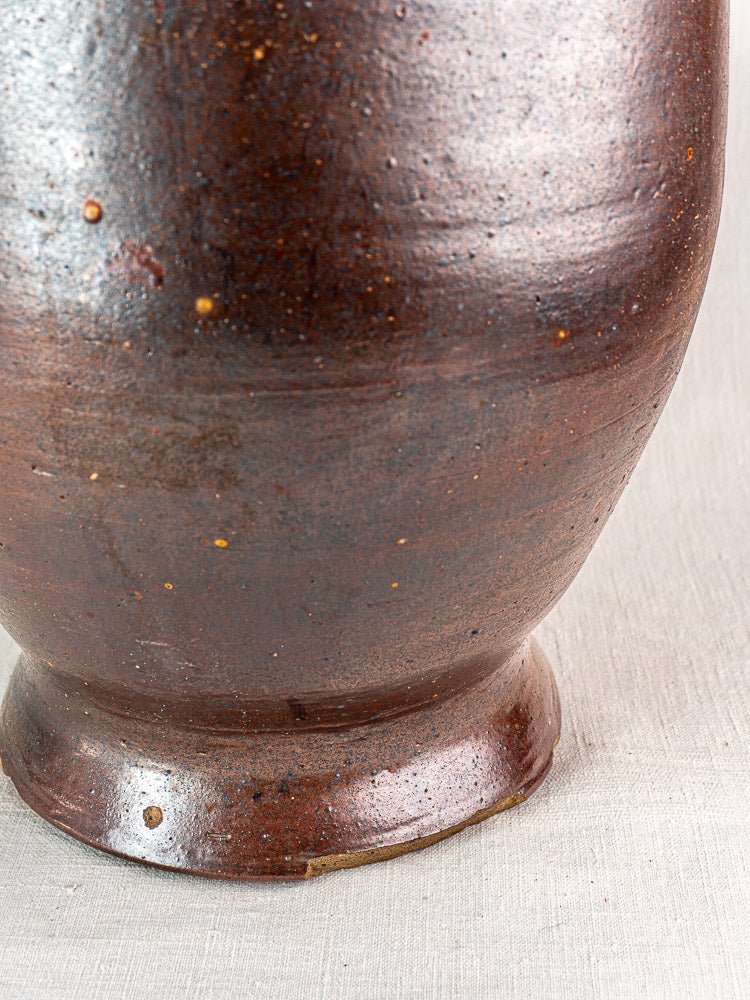 Antique French salt glazed stoneware pot à graisse with textured, speckled surface on neutral fabric.