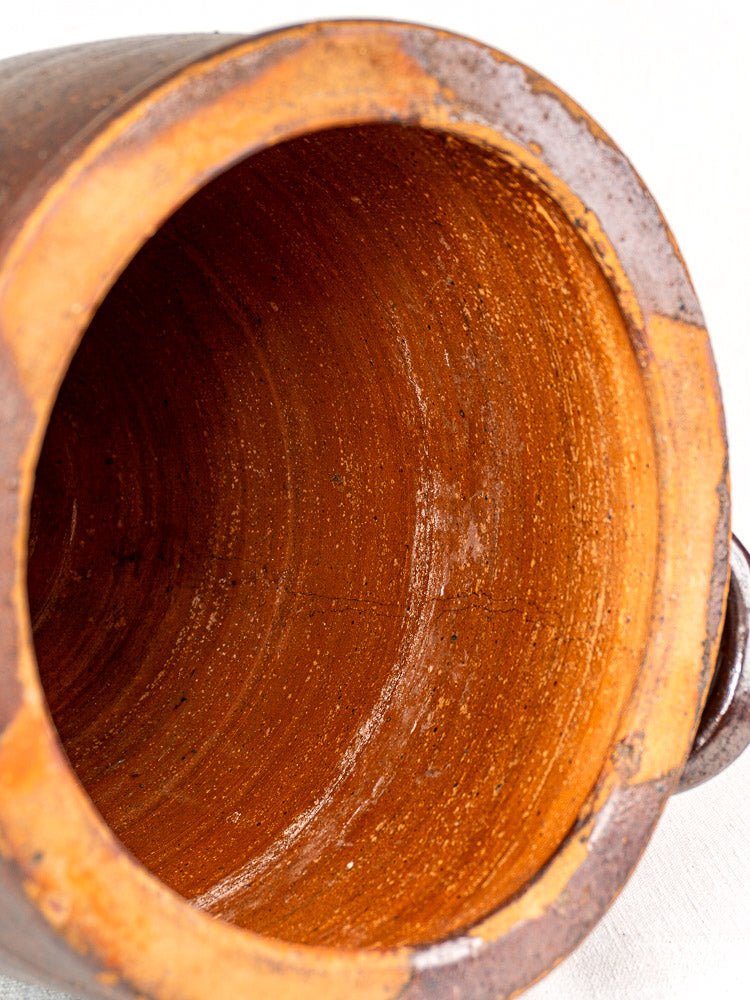Interior close-up of antique French salt-glazed stoneware pot à graisse with textured brown surface, rim, and handle.